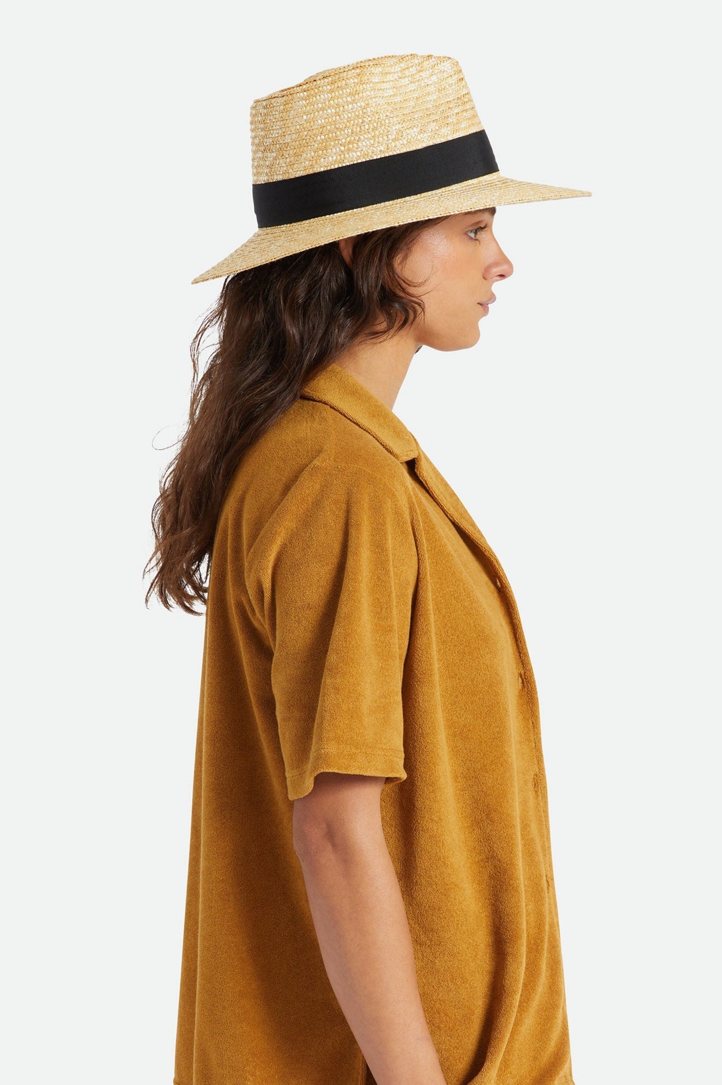 Femme portant le chapeau Barbara noir de profil, avec bord large, bande noire contrastante et style estival chic.