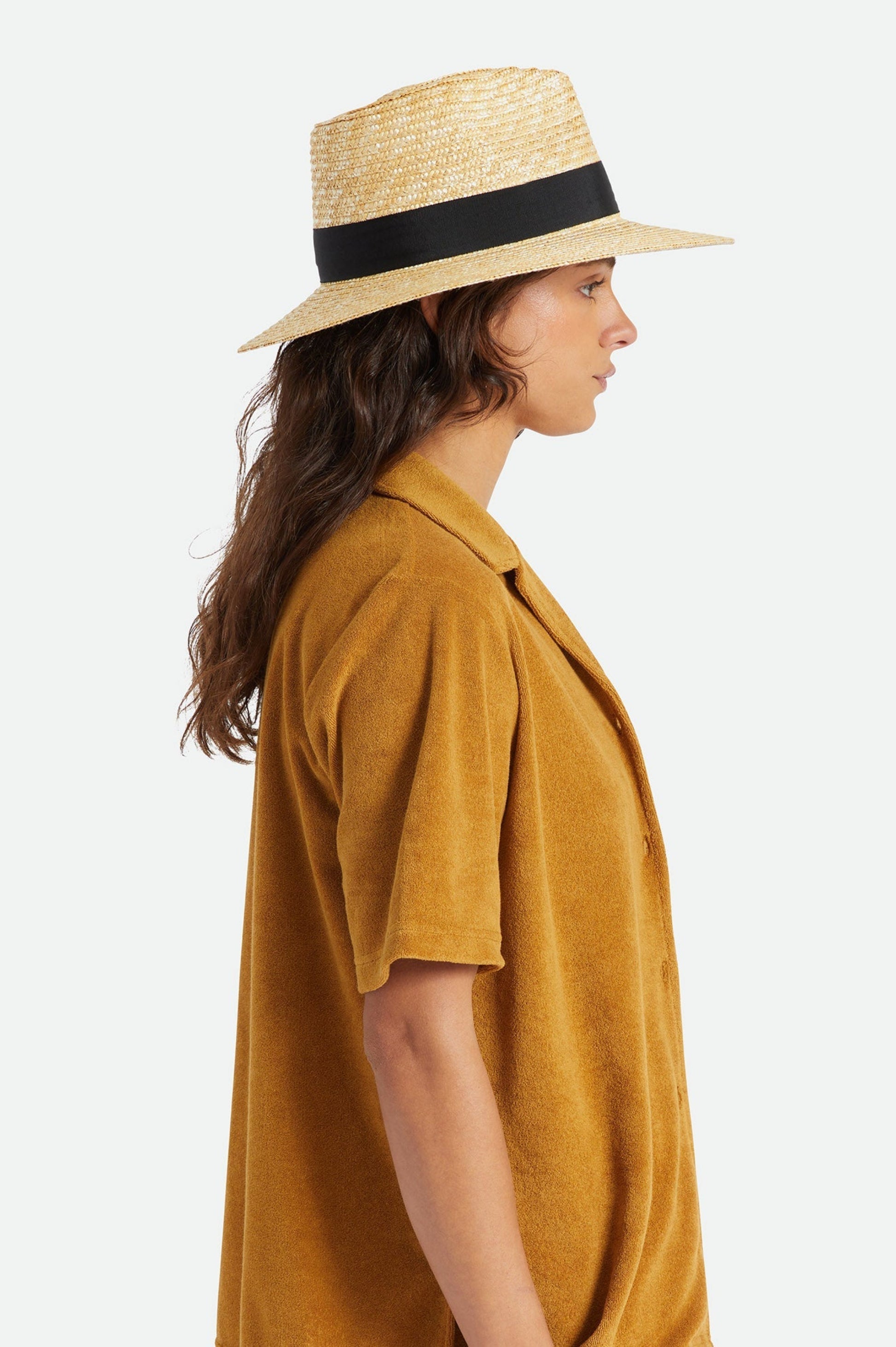 Femme portant le chapeau Barbara noir de profil, avec bord large, bande noire contrastante et style estival chic.