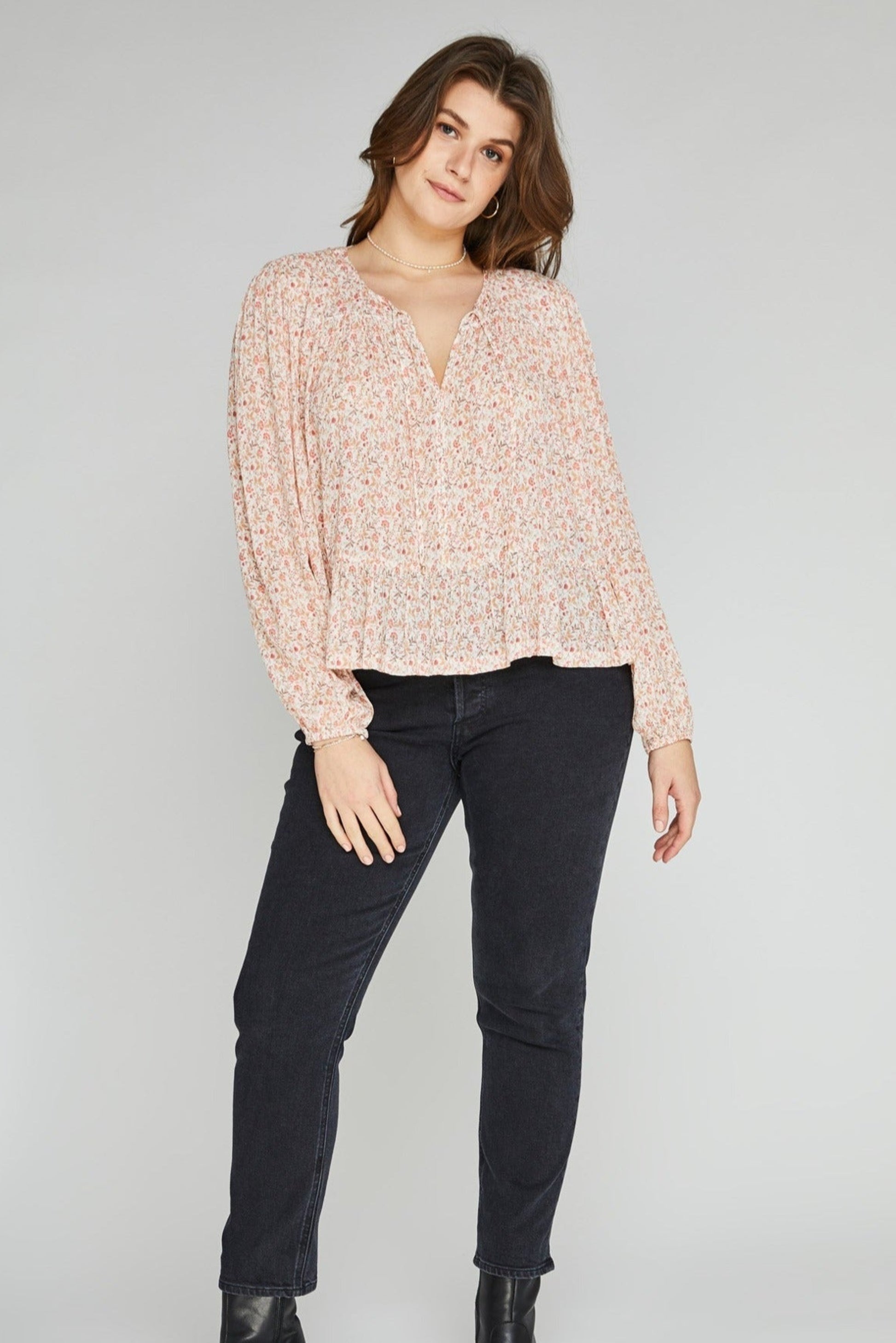 Blouse légère à imprimé fleuri abricot portée avec un jean noir.