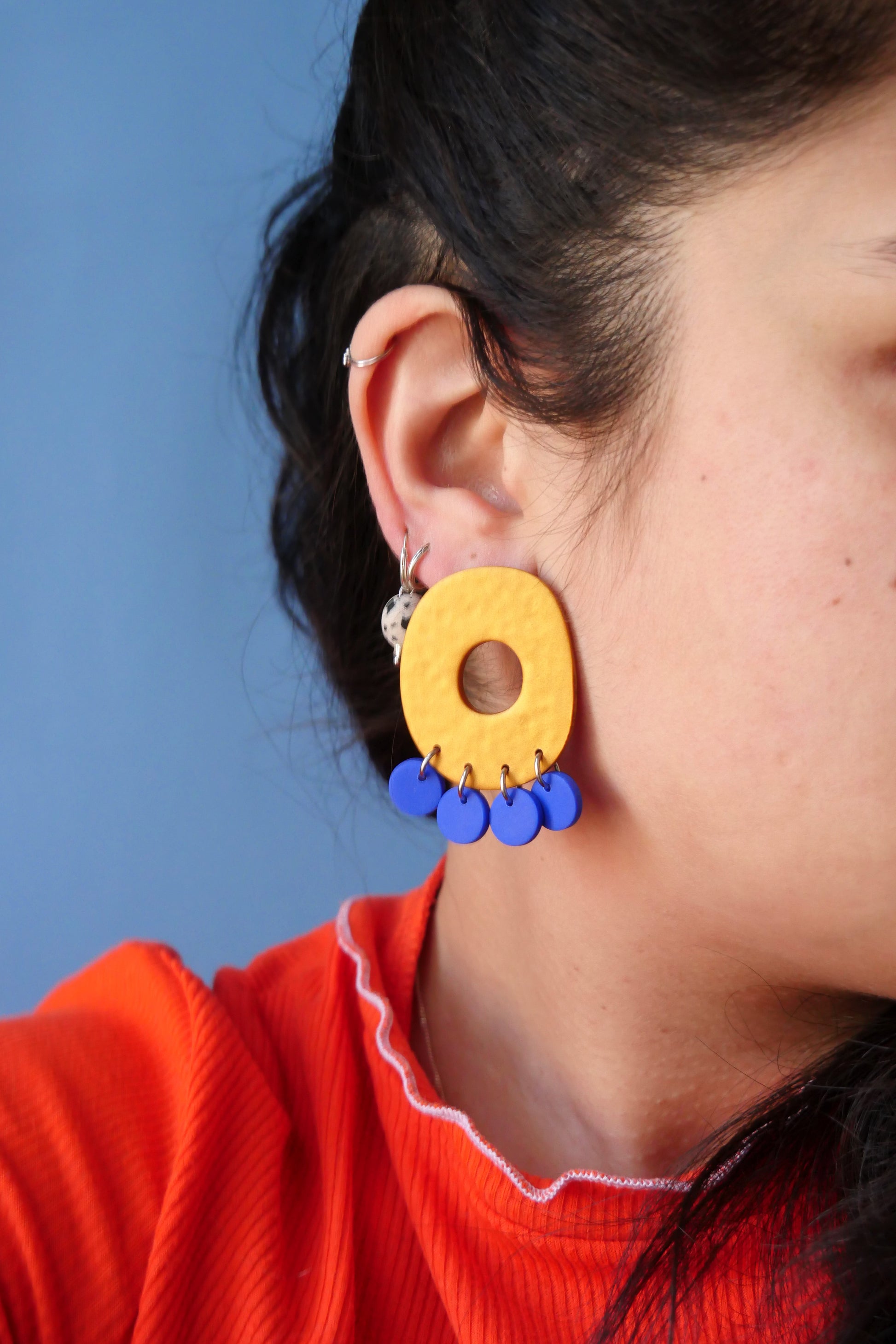 Boucles pendantes portées – anneaux or mat avec détails mobiles bleu vif en argile