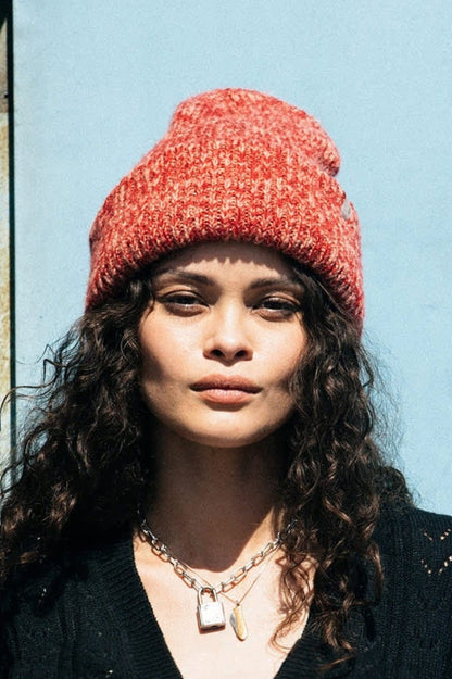 Femme portant un bonnet rouge chiné en maille épaisse, vue de face, look d’hiver tendance.