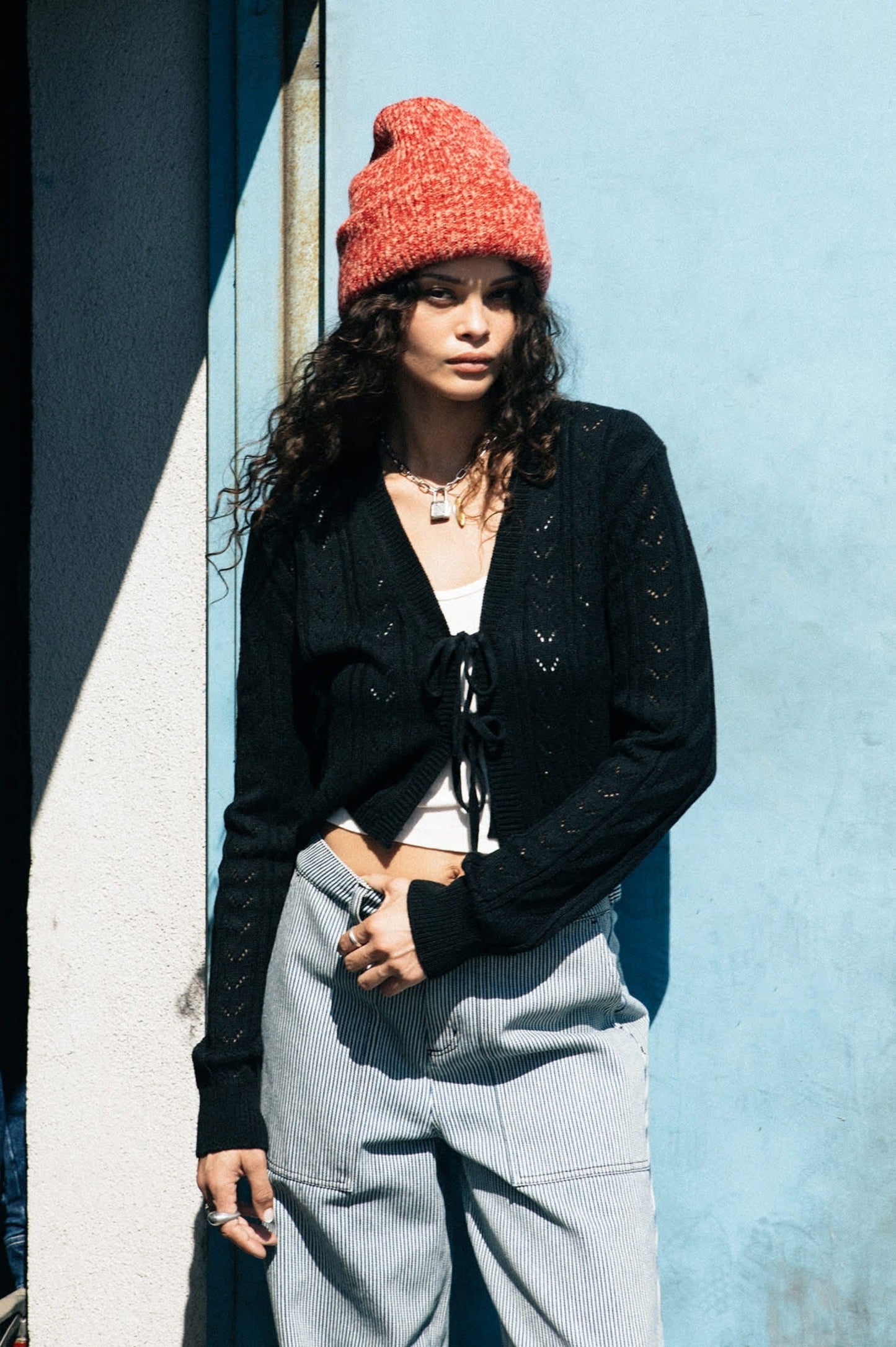 Femme portant un bonnet rouge chiné en maille épaisse, vue de profil, style urbain décontracté.