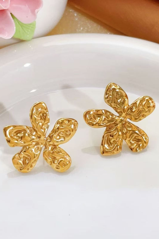 Boucles d’oreilles fleur en acier inoxydable plaqué or 18k à effet martelé posées sur une assiette blanche