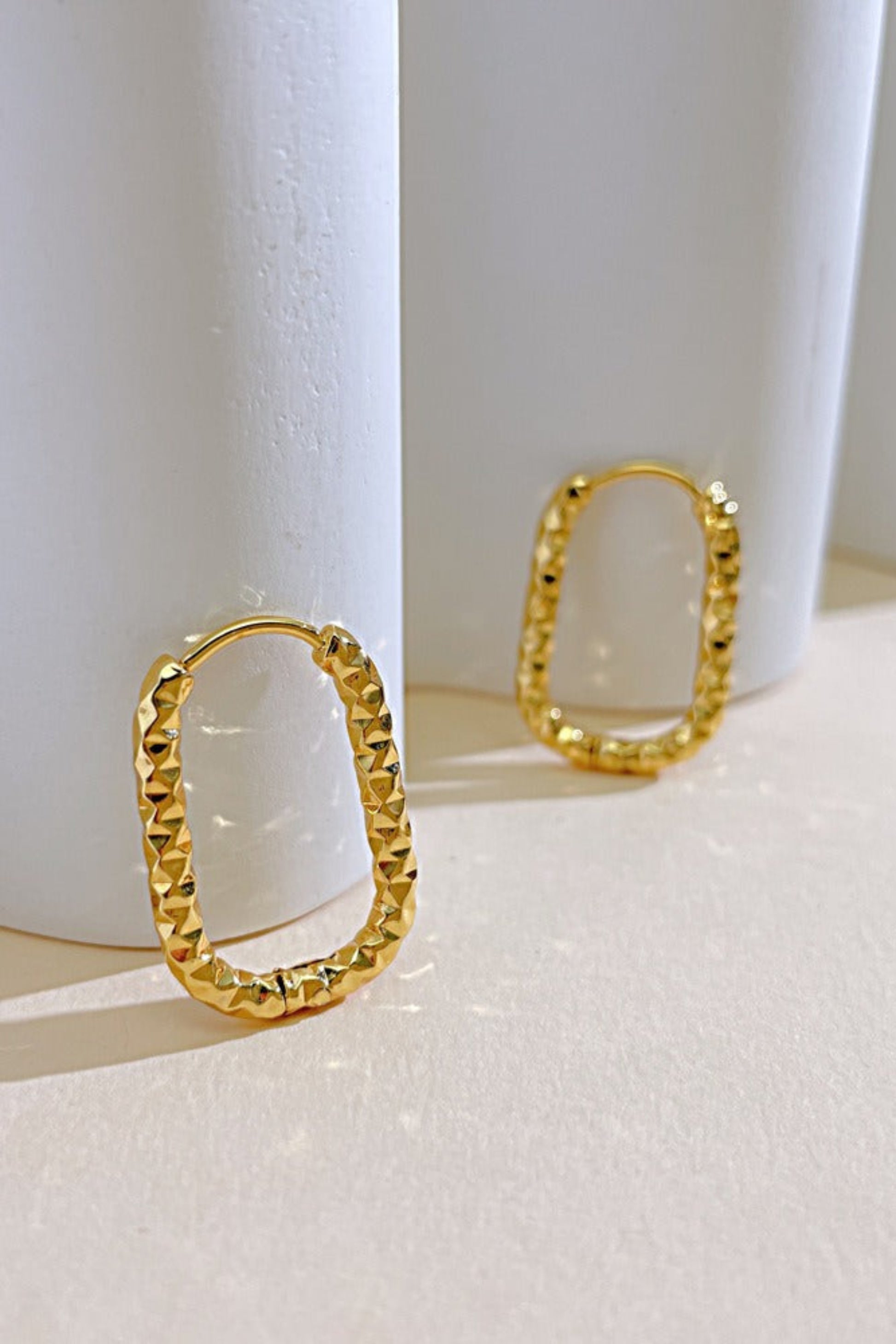 Boucles d’oreilles Cléo dorées ovales posées sur fond clair, texture martelée brillante