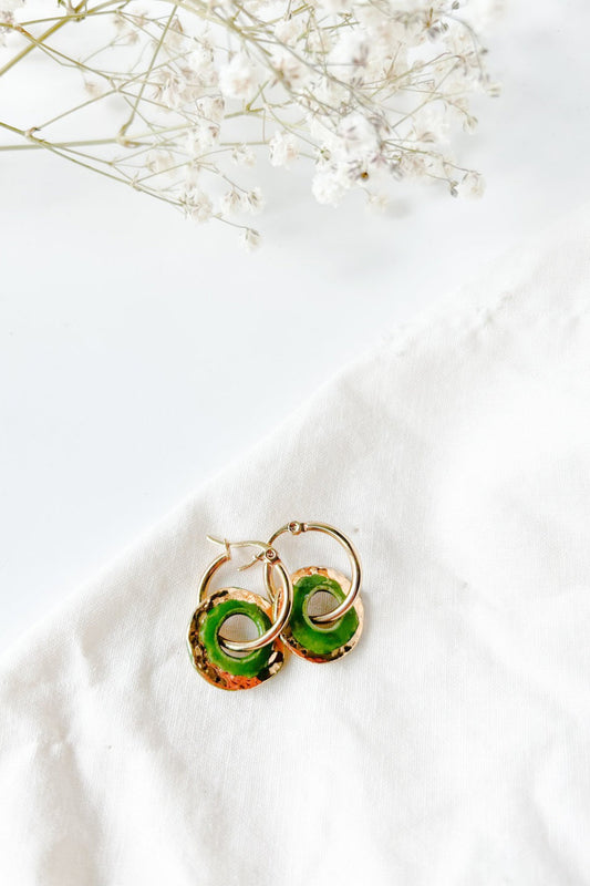 Boucles d’oreilles Alegria vert en céramique avec reflets dorés, posées sur fond blanc avec fleurs séchées