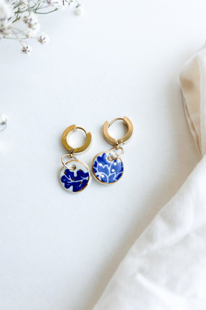 Vue de la paire de boucles d’oreilles Always bleu en céramique et or 22k, posées sur fond blanc