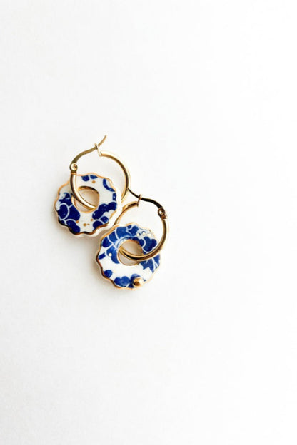 Boucles d’oreilles Donna bleu posées sur fond blanc, design rond ajouré en céramique