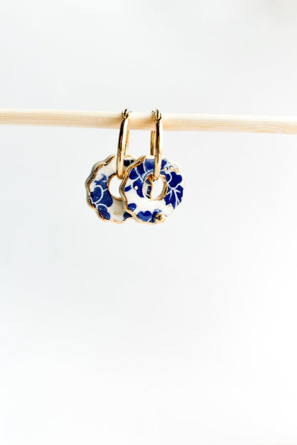 Boucles d’oreilles Donna bleu en céramique et or 22k suspendues à un support en bois clair