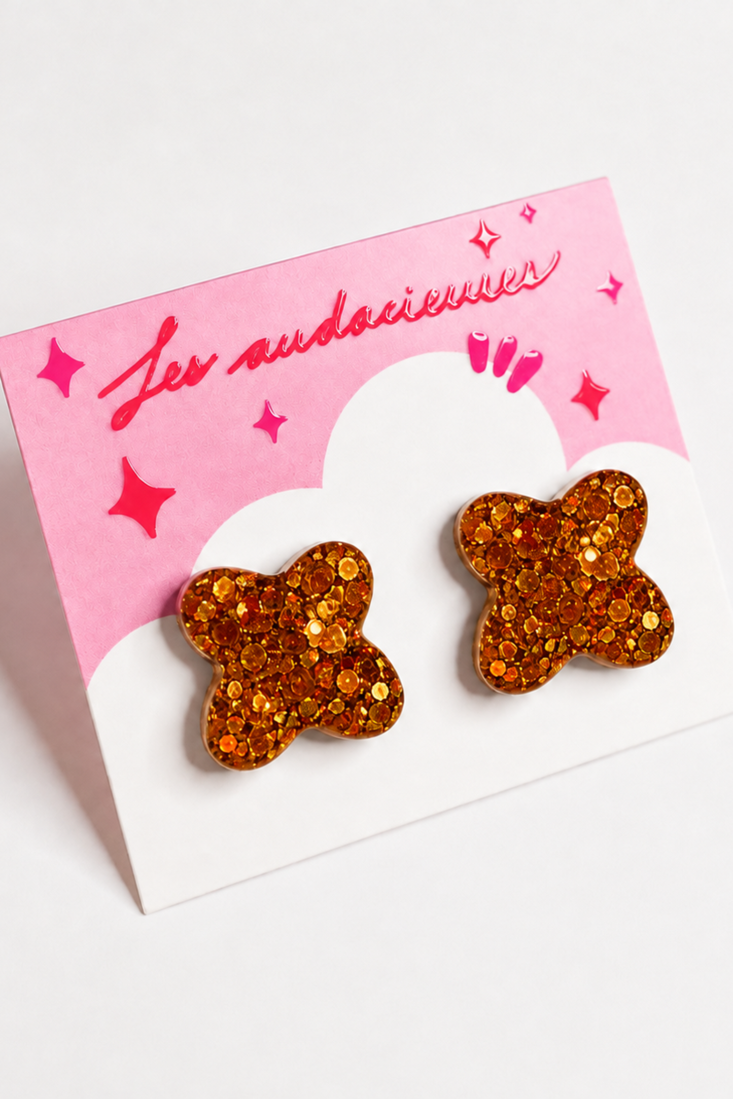 Boucles d’oreilles clou Les Audacieuses Confettis orange, en résine époxy avec confettis brillants, présentées sur carte rose.