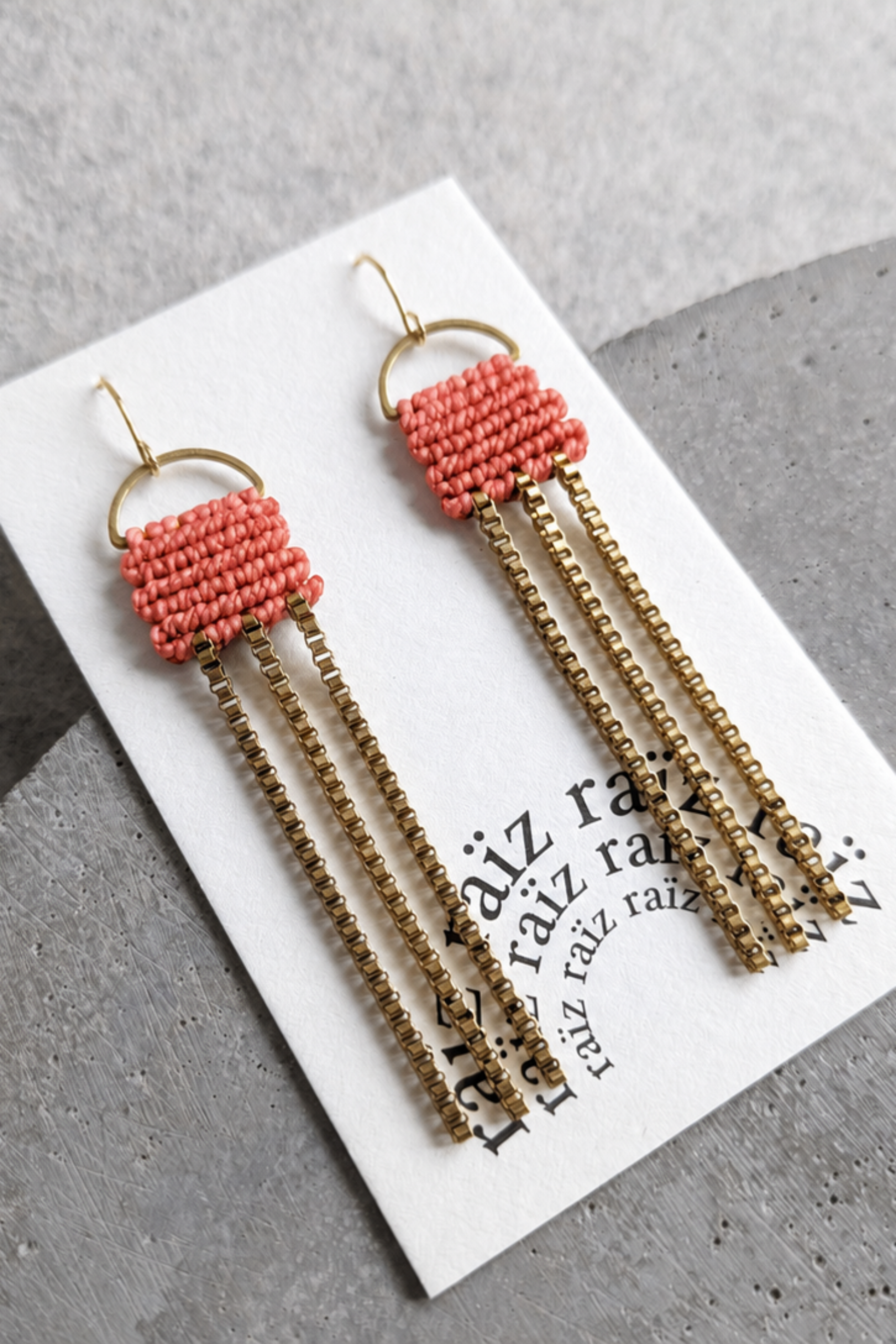 Boucles d’oreilles corail et dorées présentées sur carton, avec chaînes pendantes et style bohème chic.