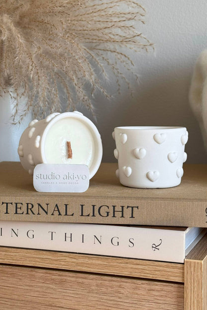 Bougie artisanale parfumée fraise et champagne, pot blanc à cœurs en relief, ambiance décorative douce.