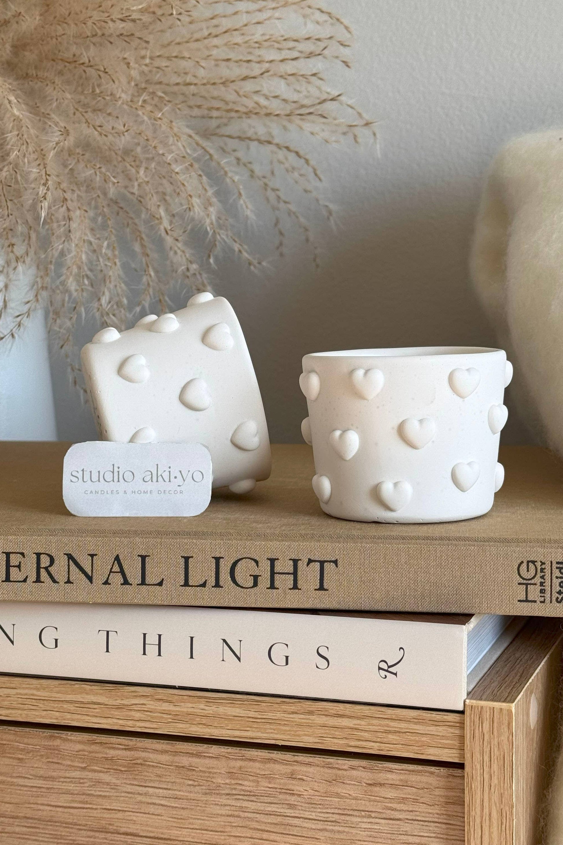 Bougie parfumée à la cire de soja, mèche en bois, pot blanc texturé avec cœurs en relief.