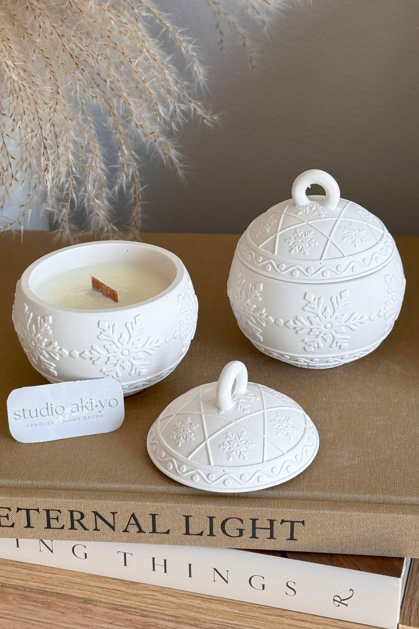 Bougie décorative artisanale en forme de boule de Noël fermée, texture flocons délicate.