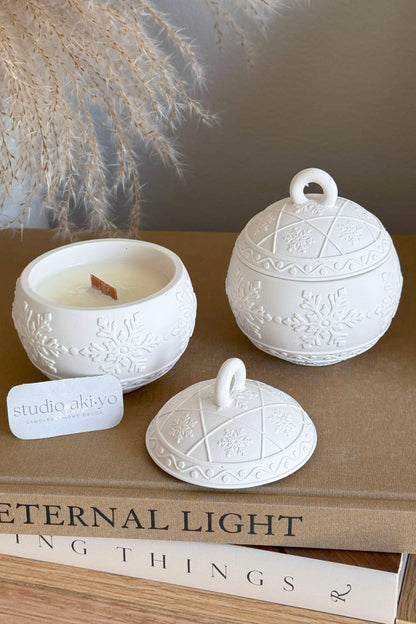 Bougie décorative artisanale en forme de boule de Noël fermée, texture flocons délicate.