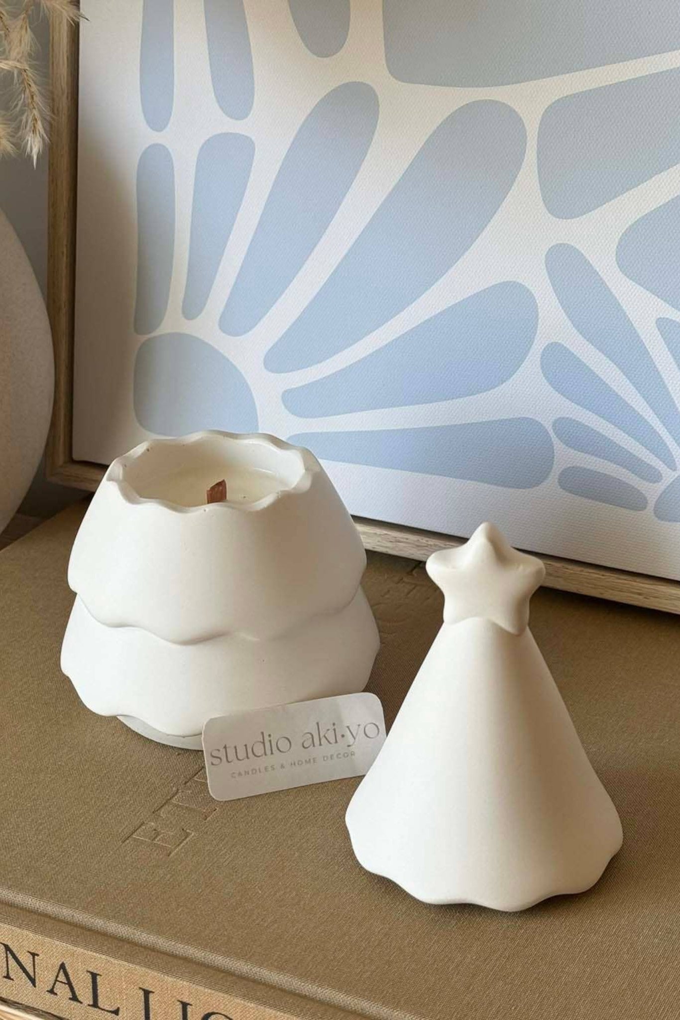 Bougie en cire de soja naturelle avec mèche en bois, pot sapin blanc et couvercle étoilé ouvert.