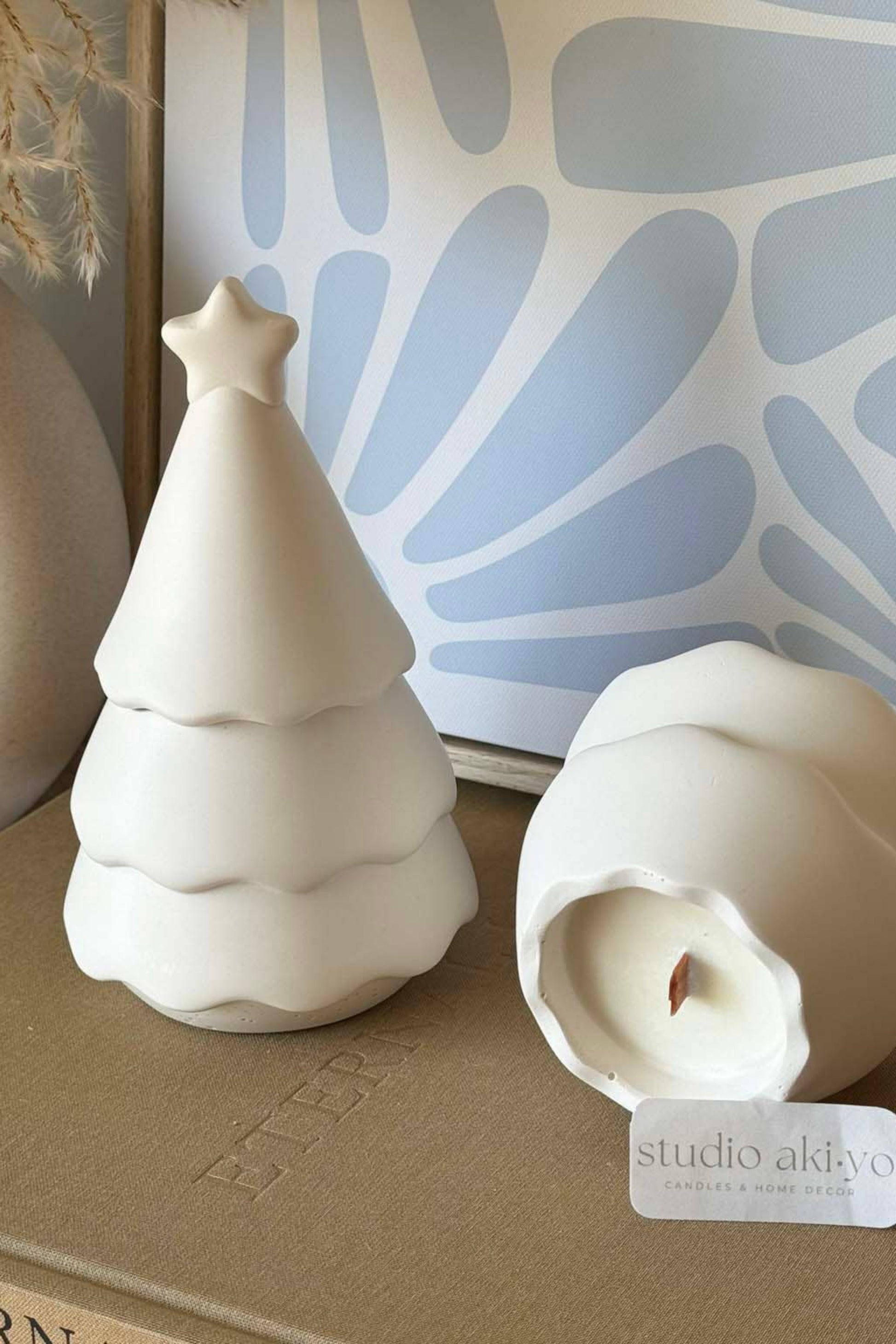 Bougie artisanale parfumée forêt enchantée, pot blanc en forme de sapin, ambiance décorative douce.