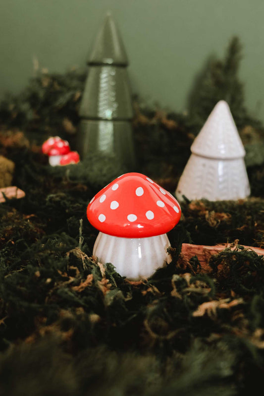 petite bougie en forme de champignon rouge décoratif dans un décor forestier, parfum forêt enchantée