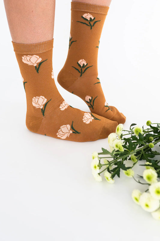  Personne portant des chaussettes couleur caramel à motif floral avec fleurs en arrière-plan