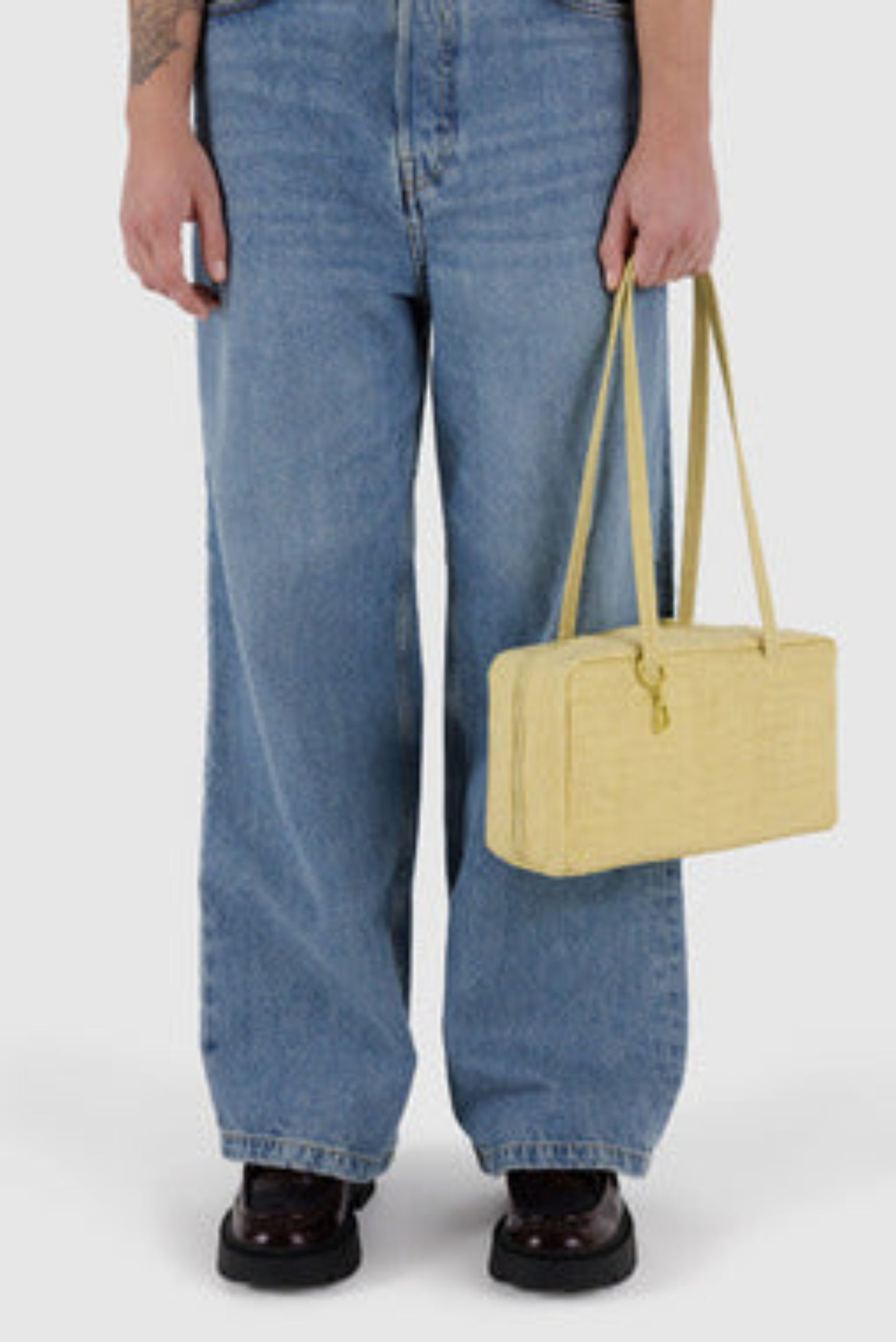 Sac Bowler Jaune porté à l’épaule avec un jean, format bowling compact en nylon recyclé.