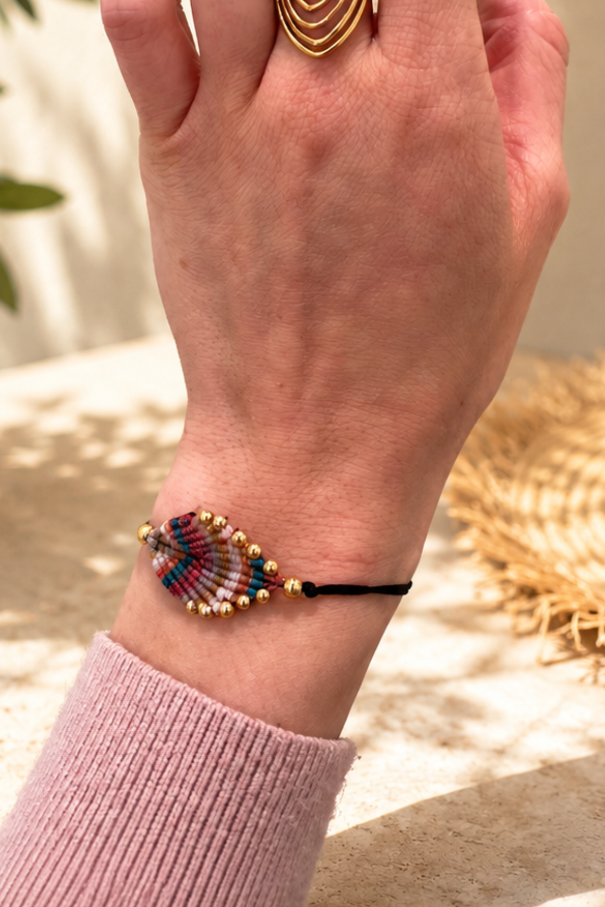 Bracelet perlé multicolore porté au poignet dans un décor estival bohème chic