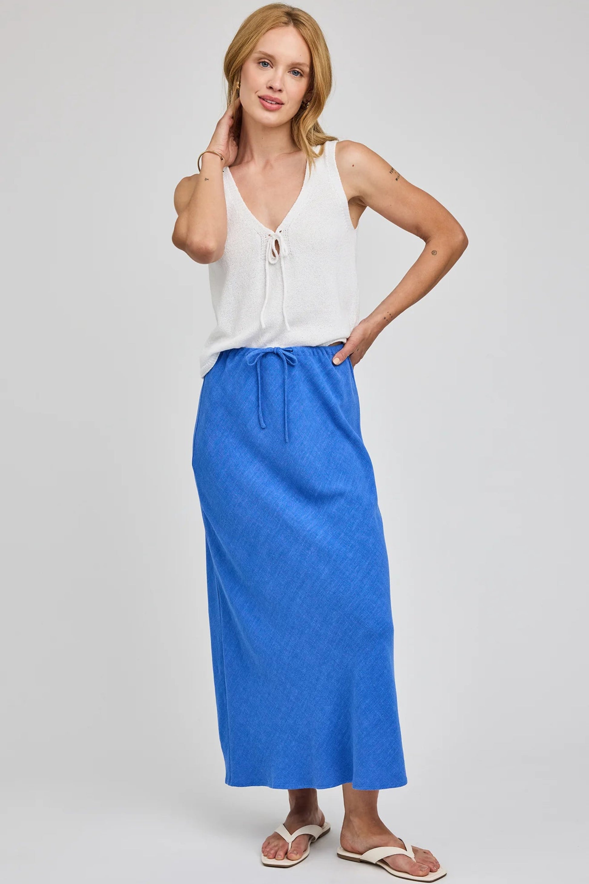 Jupe Britanny bleu portée avec un haut blanc et des sandales pour un look estival chic décontracté.