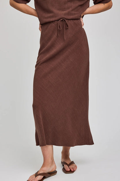 Jupe midi Britanny espresso portée de face avec taille ajustable, cordon et tombé fluide en rayonne et lin.