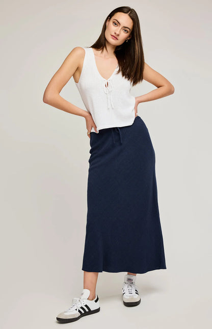 Jupe Britanny marine portée avec un haut blanc et des baskets pour un look chic décontracté.