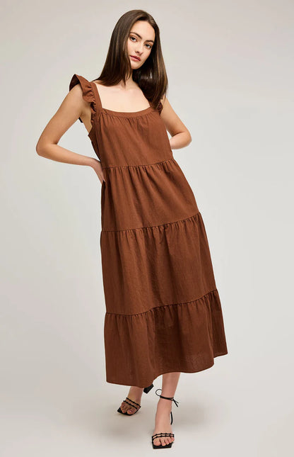 Robe longue de couleur cappuccino avec une coupe fluide et ample. Son encolure carrée met en valeur le décolleté, tandis que les bretelles volantées ajoutent une touche romantique. La robe est confectionnée en plusieurs étages froncés, créant un effet aérien et léger. Idéale pour les journées ensoleillées, elle se porte aussi bien avec des sandales plates que des talons pour un look plus sophistiqué.