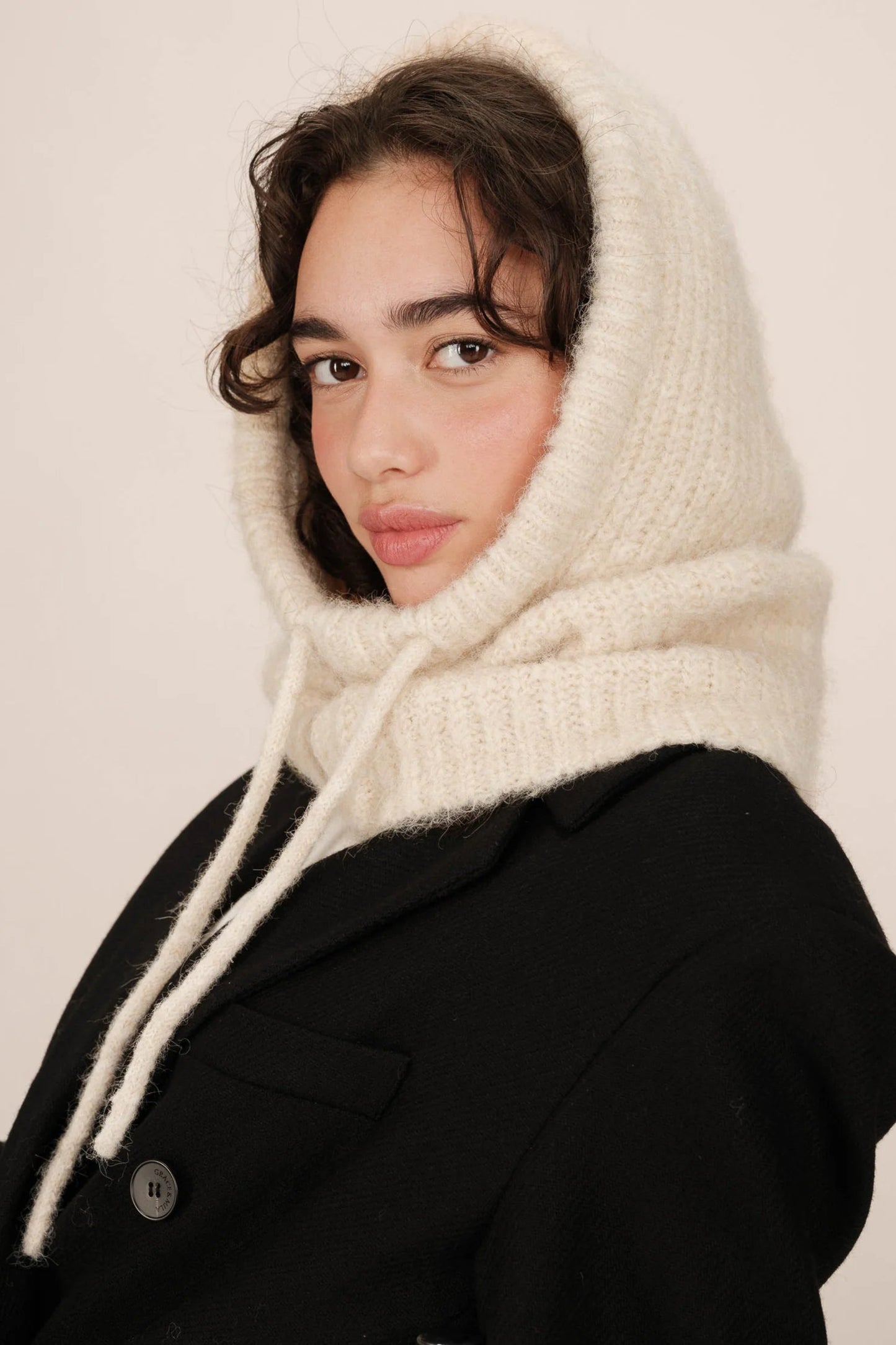 Modèle portant la capuche Roma crème – look chaleureux, maille douce et protectrice.
