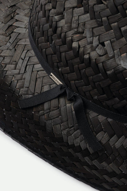 Gros plan du ruban noir noué sur le chapeau en paille tressée – finition soignée et élégante