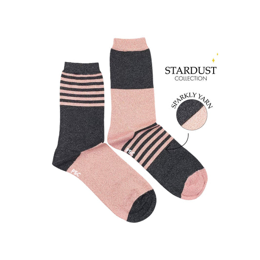 Paire de chaussettes dépareillées sur fond blanc. Les deux chaussettes sont de couleur gris et rose et les motifs s’alternent entre des lignes et des larges bandes. Ce sont des chaussettes à paillettes.  