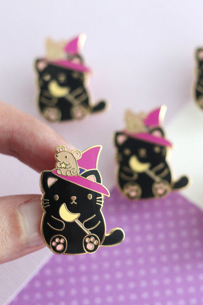 Épinglette chat sorcier tenue entre les doigts – finition doree