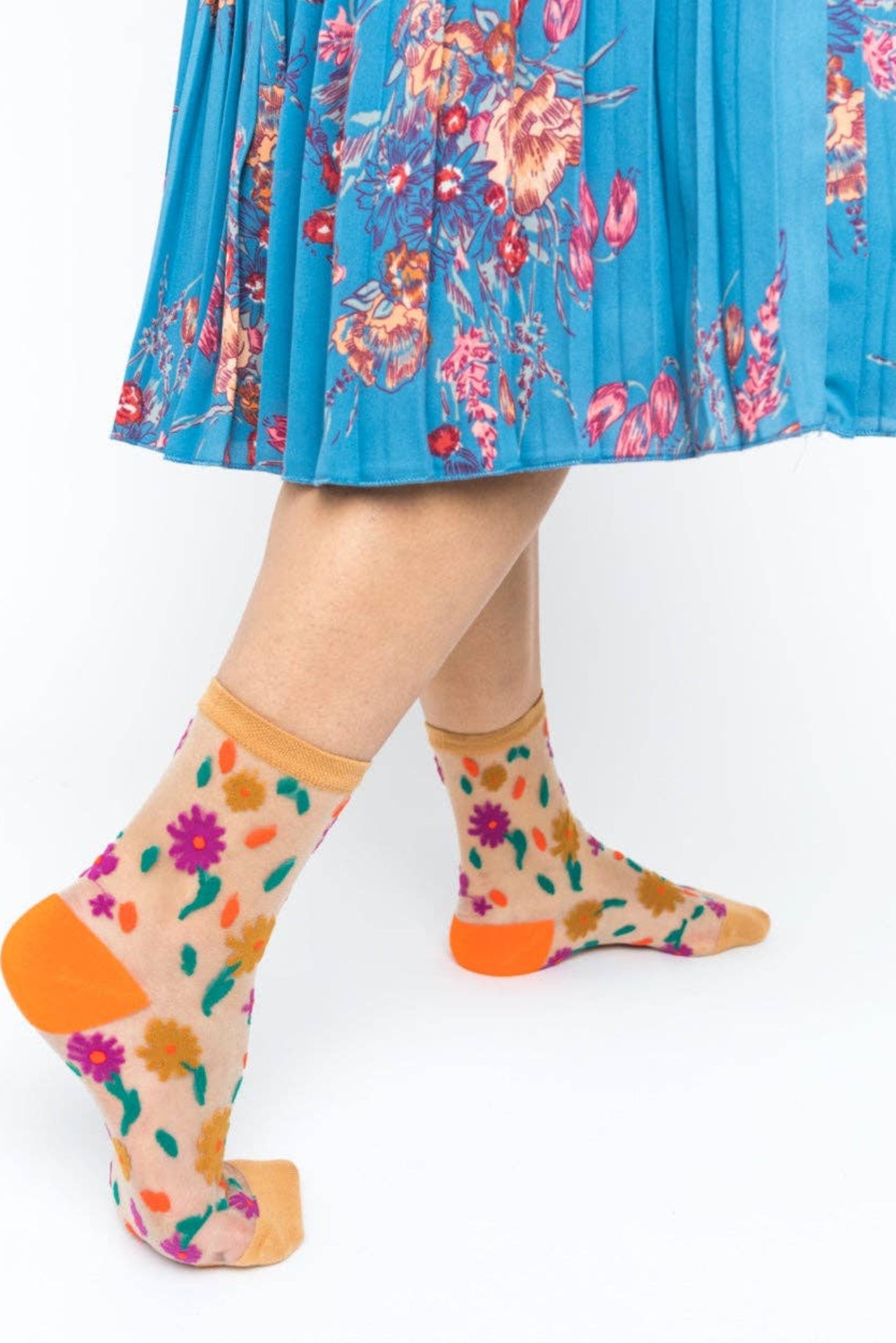 Chaussettes transparentes à fleurs colorées portées avec jupe bleue
