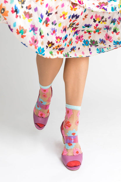 Chaussettes transparentes fleuries portées avec sandales à talons et une robe fleurie