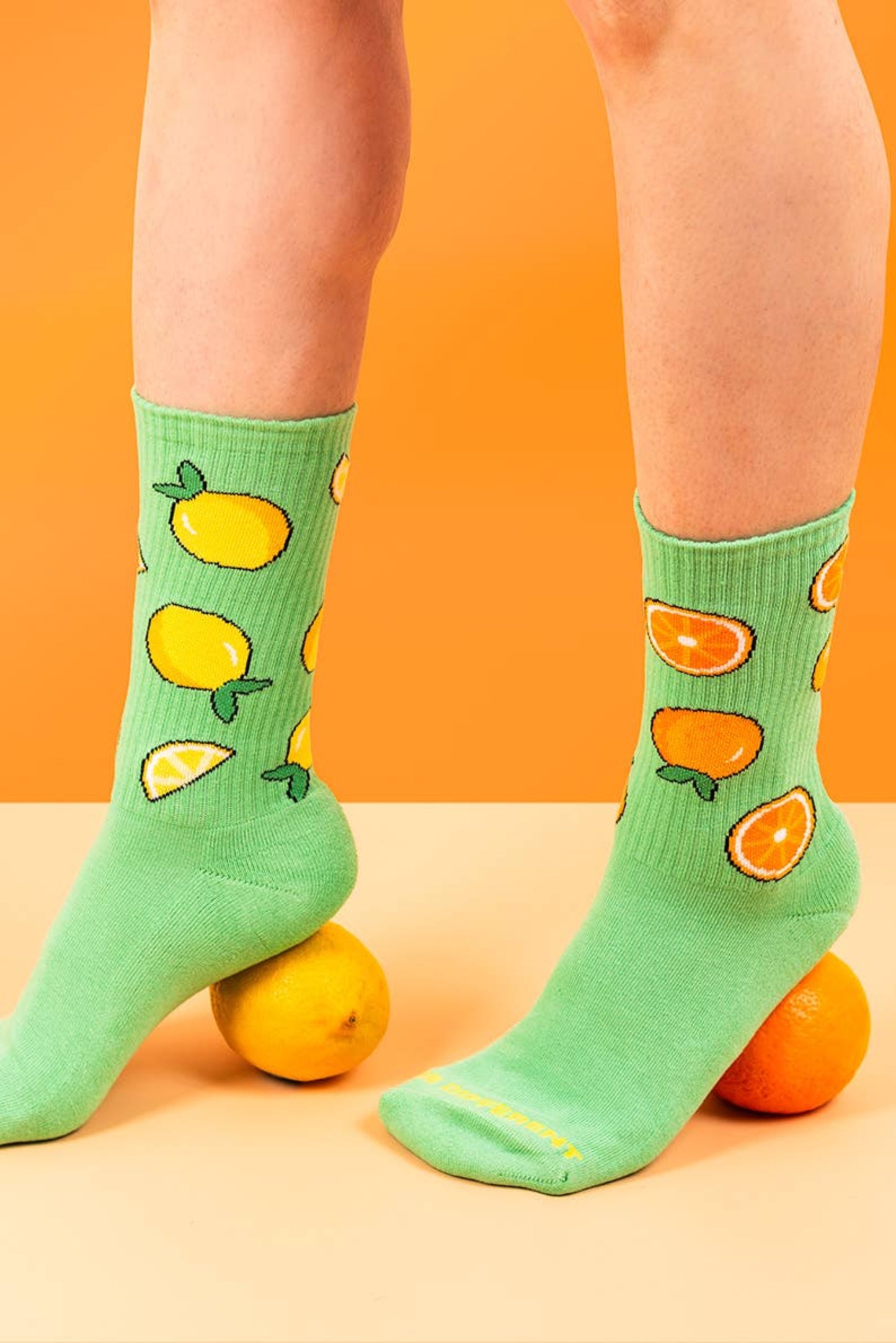 Chaussettes fruitees portees sur fond colore avec citrons et oranges