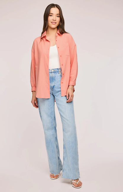 Chemise Callahan couleur Bellini en coton léger. Modèle ample et fluide avec manches longues, col classique et fermeture boutonnée. Une poche plaquée sur la poitrine ajoute une touche décontractée. Portée ouverte sur un débardeur blanc et un jean bleu clair pour un look casual et tendance.