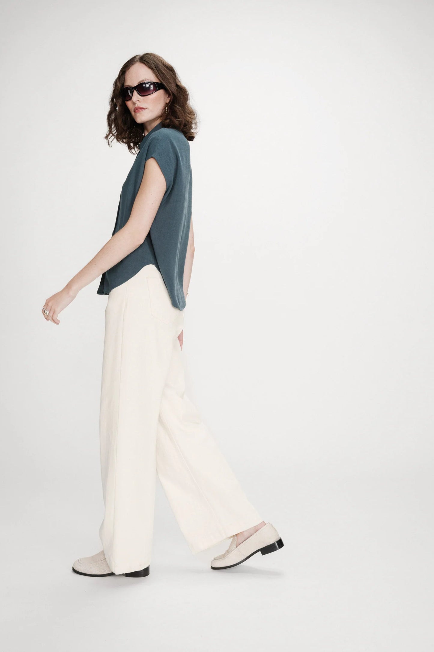 Look complet avec chemise émeraude et pantalon clair vu de dos