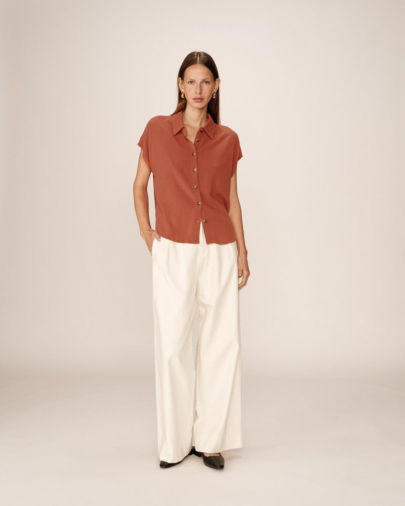 Chemise fluide terracotta portée avec pantalon blanc – Look décontracté chic