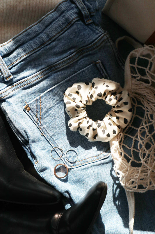 Chouchou en coton bio blanc à pois noirs posé sur un jean en ambiance lifestyle