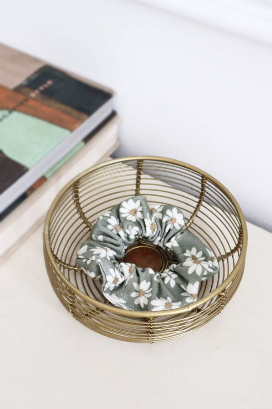 Chouchou vert sauge à motifs fleuris présenté dans un panier déco