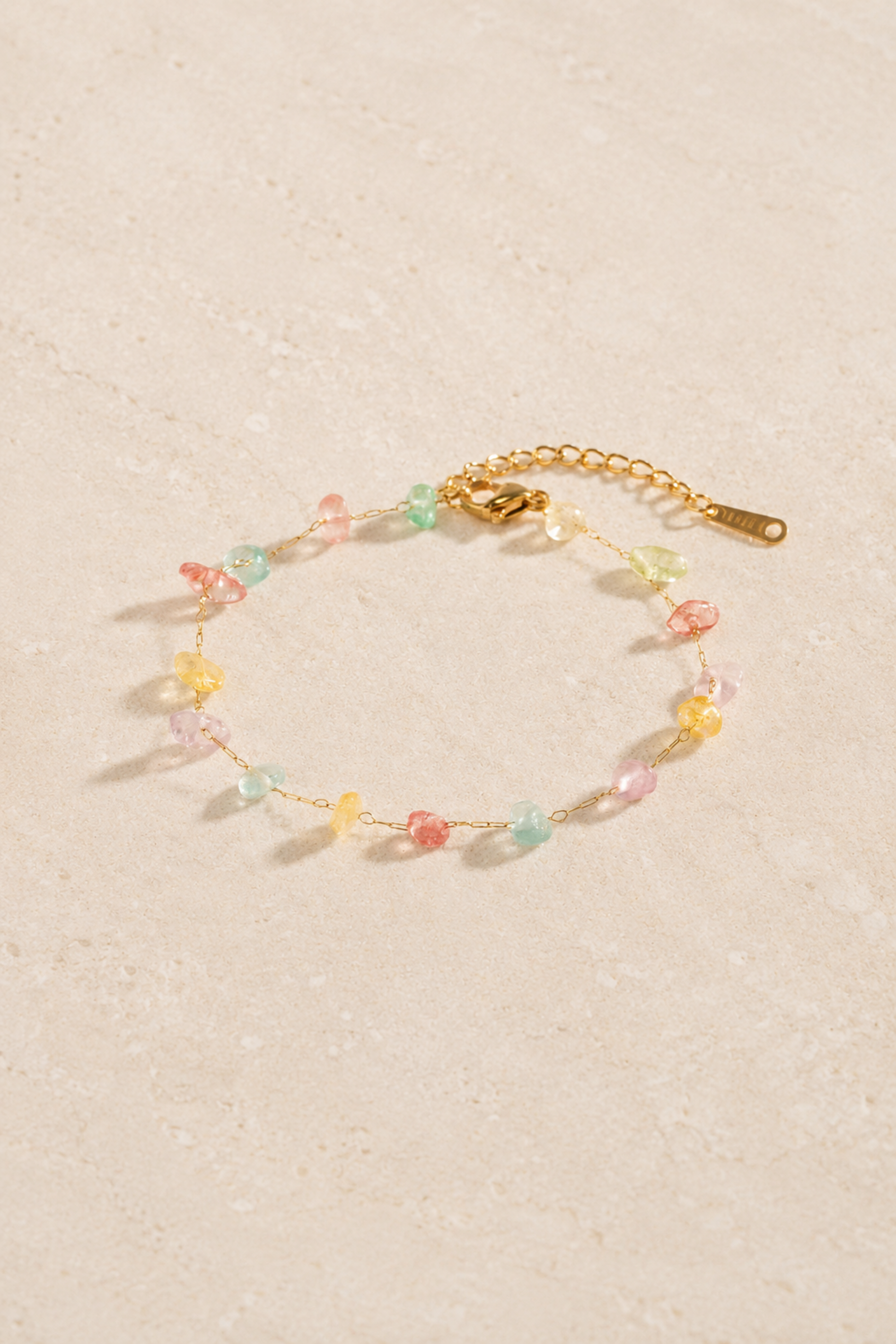 Bracelet Clochette Or avec chaîne dorée fine et petites pierres colorées pastel.