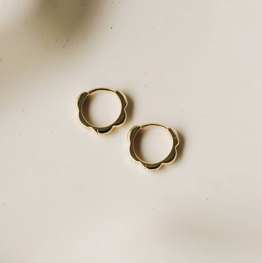 Paire de créoles Colio posées sur une assiette, en plaqué or – Vue détaillée du motif ondulé