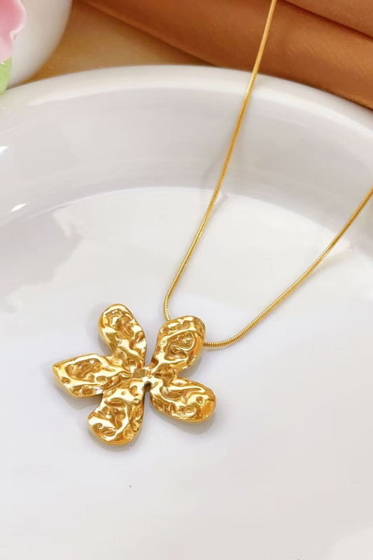 Collier en acier inoxydable plaqué or 18k avec pendentif fleur martelée sur assiette blanche