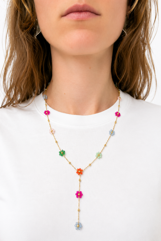 Collier doré avec petites fleurs multicolores porté sur un chandail blanc minimaliste