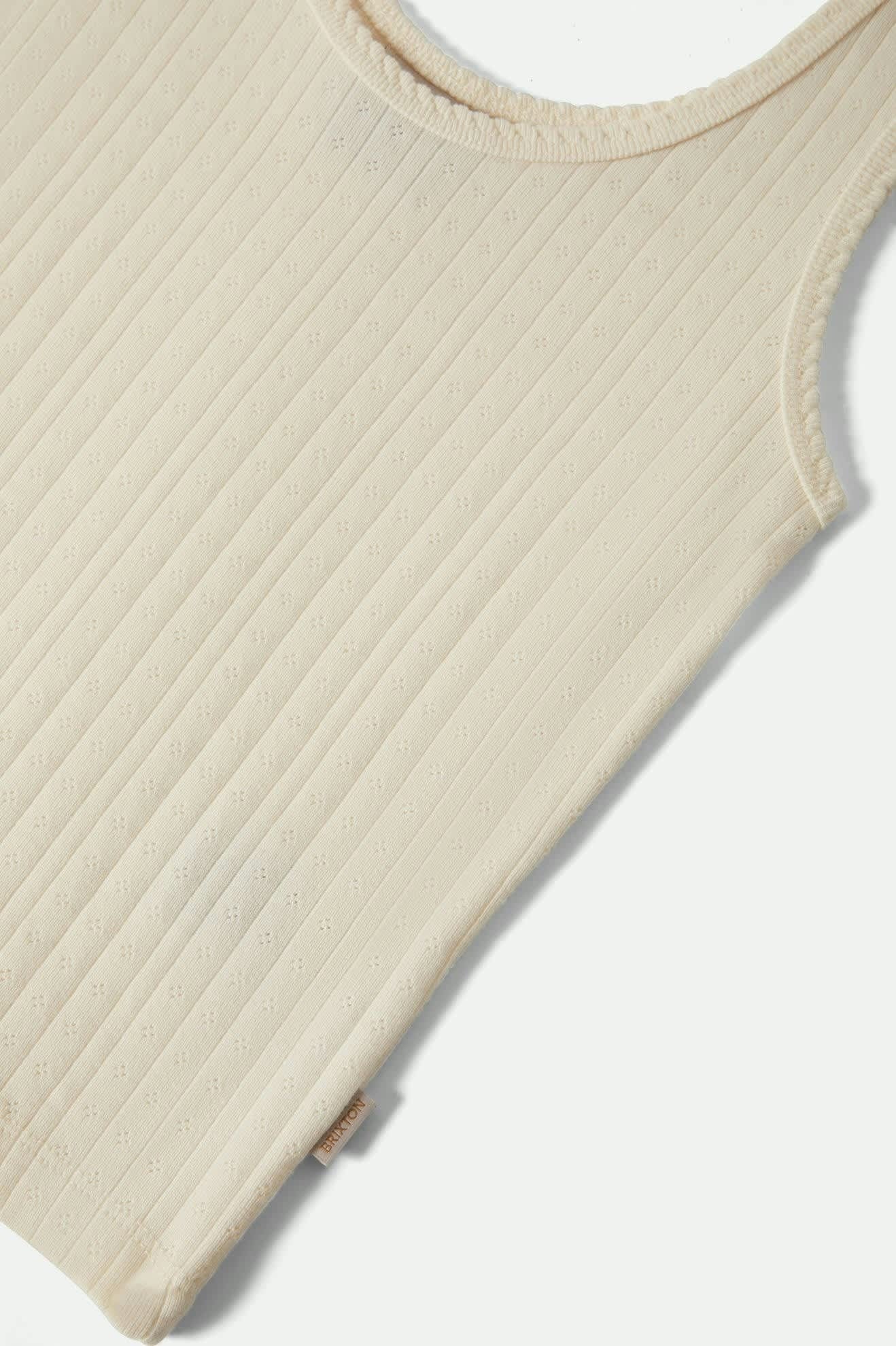 Détail bas du débardeur pointelle blanc avec étiquette latérale