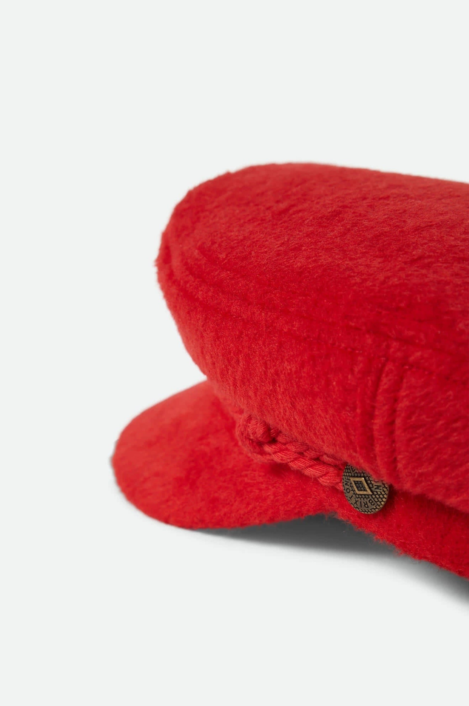 Gros plan sur la texture laineuse rouge et le cordon avant de la casquette Fiona