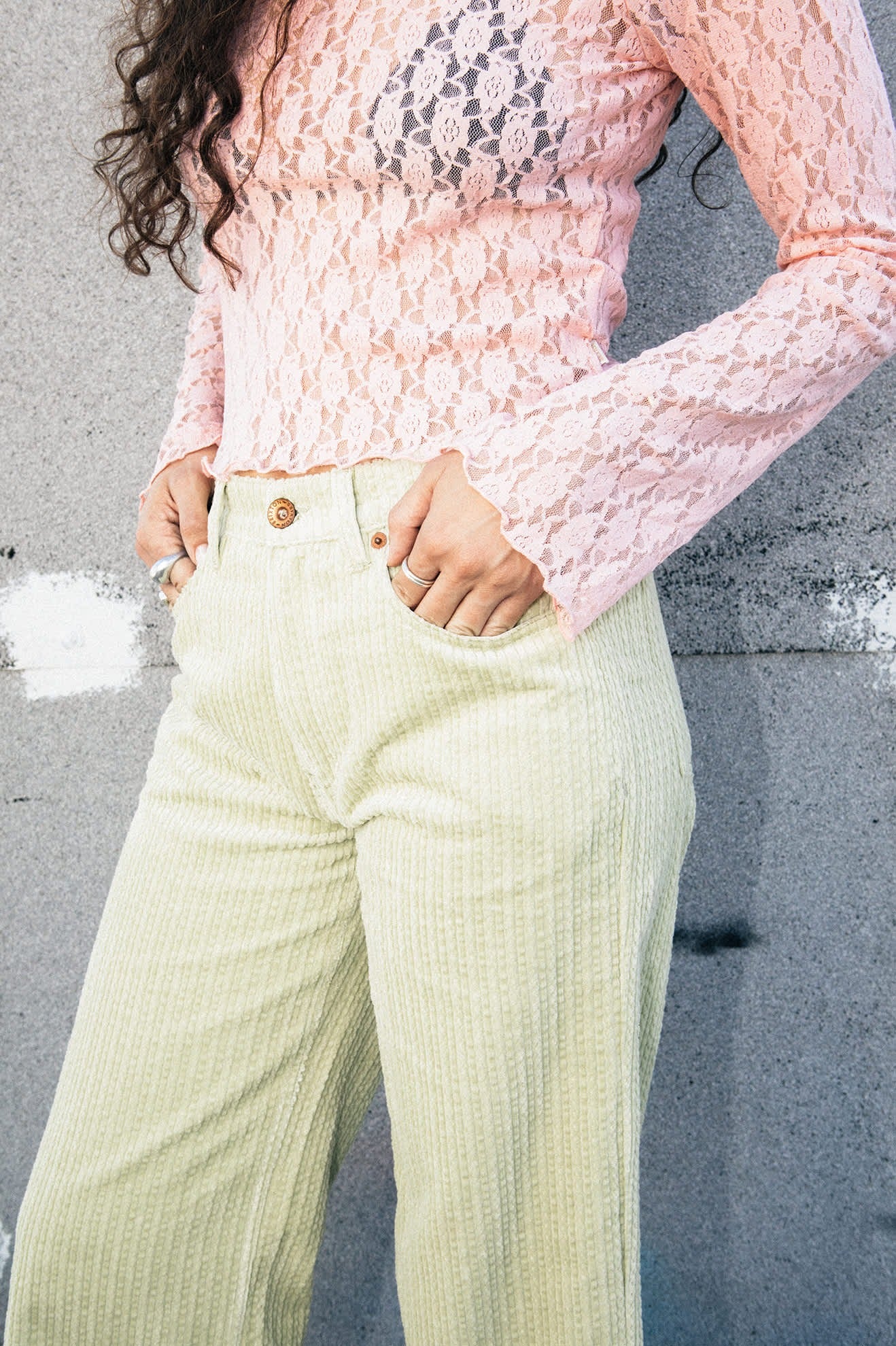 Détail du haut Dolly en dentelle rose porté avec pantalon vert – manches évasées et dentelle florale