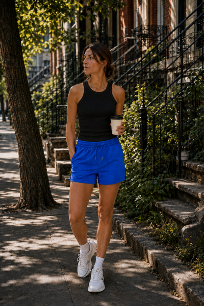 Camisole de sport noire portée avec short bleu dans un look urbain décontracté et sportif.