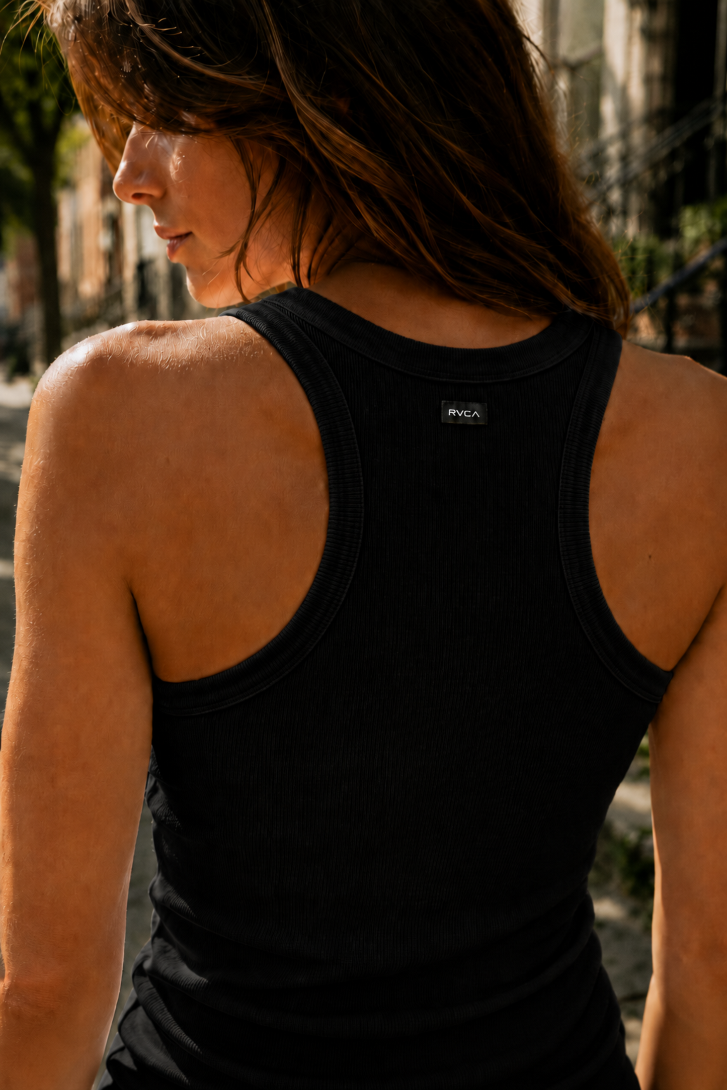 Camisole de sport noire côtelée vue de dos avec coupe dos nageur et tissu à séchage rapide.