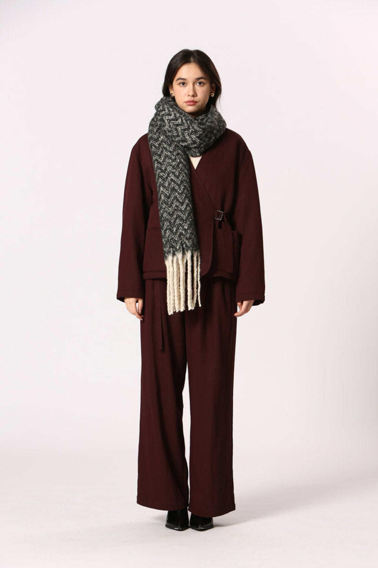 Écharpe noire à motif chevron avec franges blanches, portée sur ensemble bordeaux